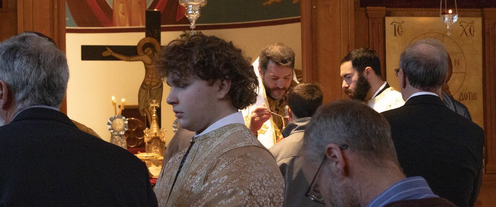 An altar server holding a candle beside the altar during a service.