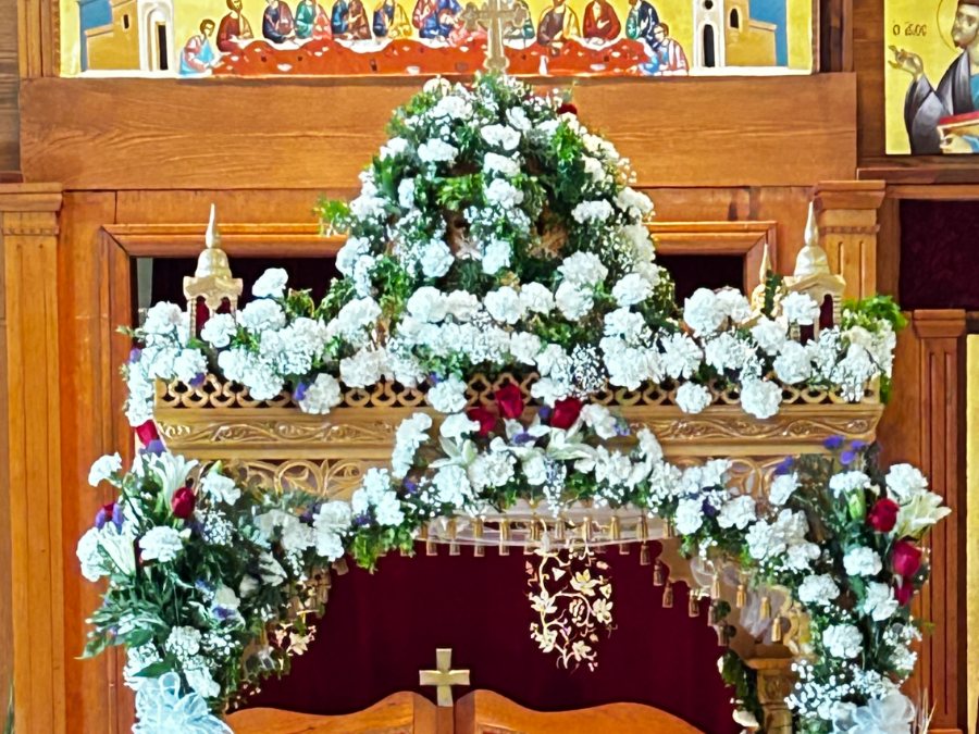 The epitaphios canopy banked with white carnations and greenery, standing before the royal doors.